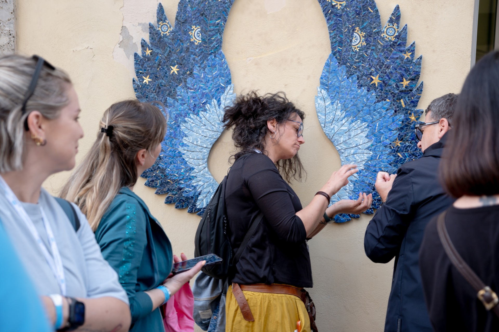 Persone con sordocecità toccano con mano manufatti presso il Laboratorio Mosaico di Ravenna, in occasione della gita organizzata durante la Conferenza delle Persone Sordocieche