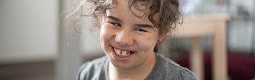 Giulia, bambina di 10 anni seguita al Centro di Osimo, sorride seduta per terra in un'aula del Centro Nazionale