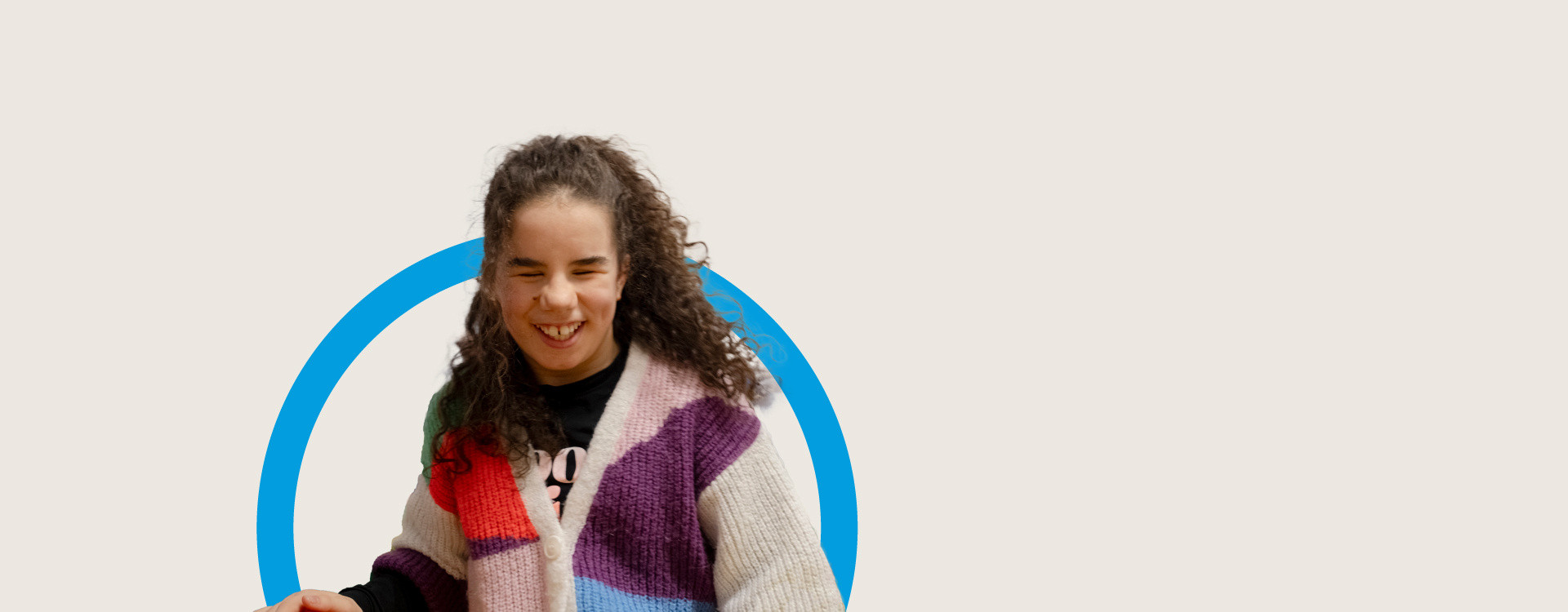 Immagine in primo piano di Giuli, una adolescente che sordocieca. Giulia ha capelli ricci, castani, indossa un maglione colorato. E' sorridente