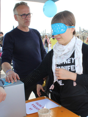 Attività di sensibilizzazione svolta dalla Sede di Padova: uno stand allestito in occasione di un evento. Una ragazza sta provando un piccolo laboratorio sensoriale preparato per l'occasione per il pubblico