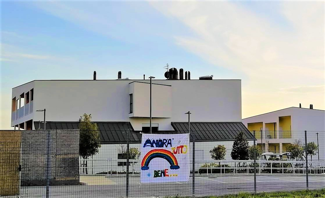 Gli edifici del nuovo Centro Nazionale, con uno striscione dove c'è la scritta in lettere colorate "Andrà tutto bene" e un arcobaleno.