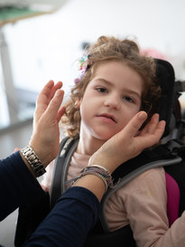 Le mani dell'educatrice si stanno avvicinando al visino di Melissa per accarezzarla
