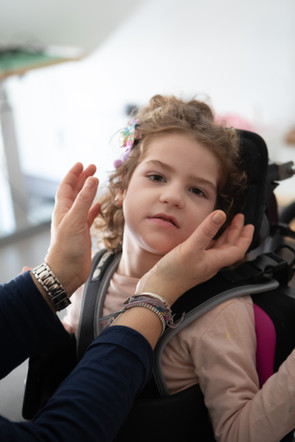 Le mani dell'educatrice si stanno avvicinando al visino di Melissa per accarezzarla