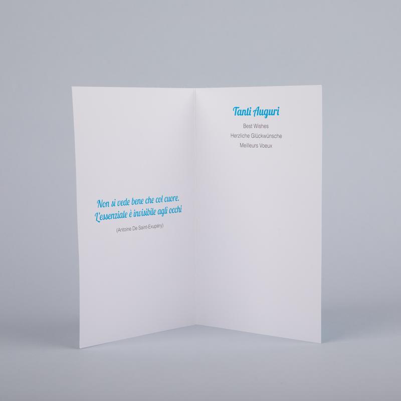 Interno del biglietto di auguri "albero azzurro". Scritta "Tanti auguri" in italiano, inglese, tedesco e francese. All'interno del biglietto è stampata la frase "Non si vede bene che col cuore. L'essenziale è invisibile agli occhi".