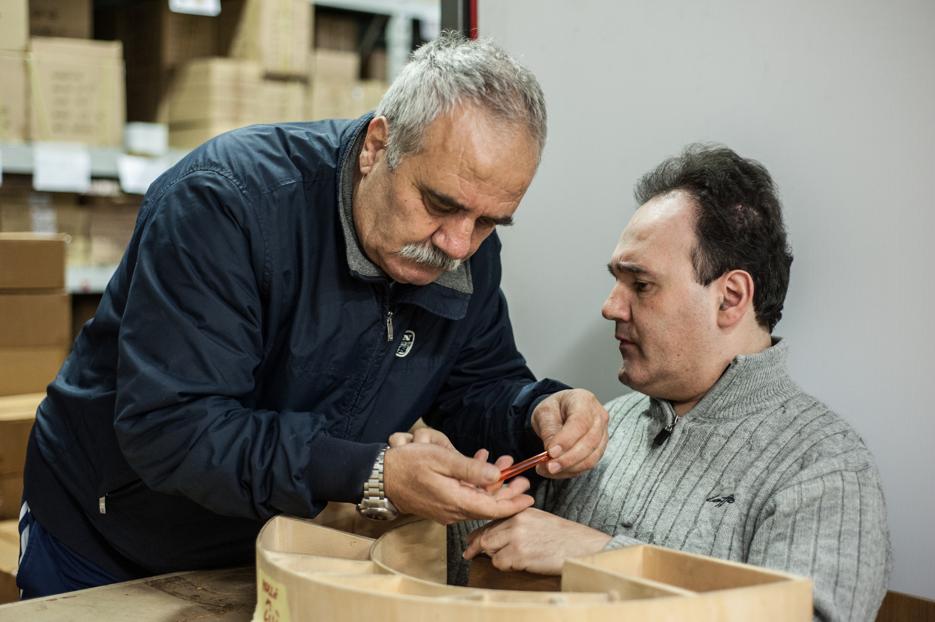 Alberto, un utente adulto, e suo padre Gianfranco, lavorano insieme un oggetto fatto di legno.
