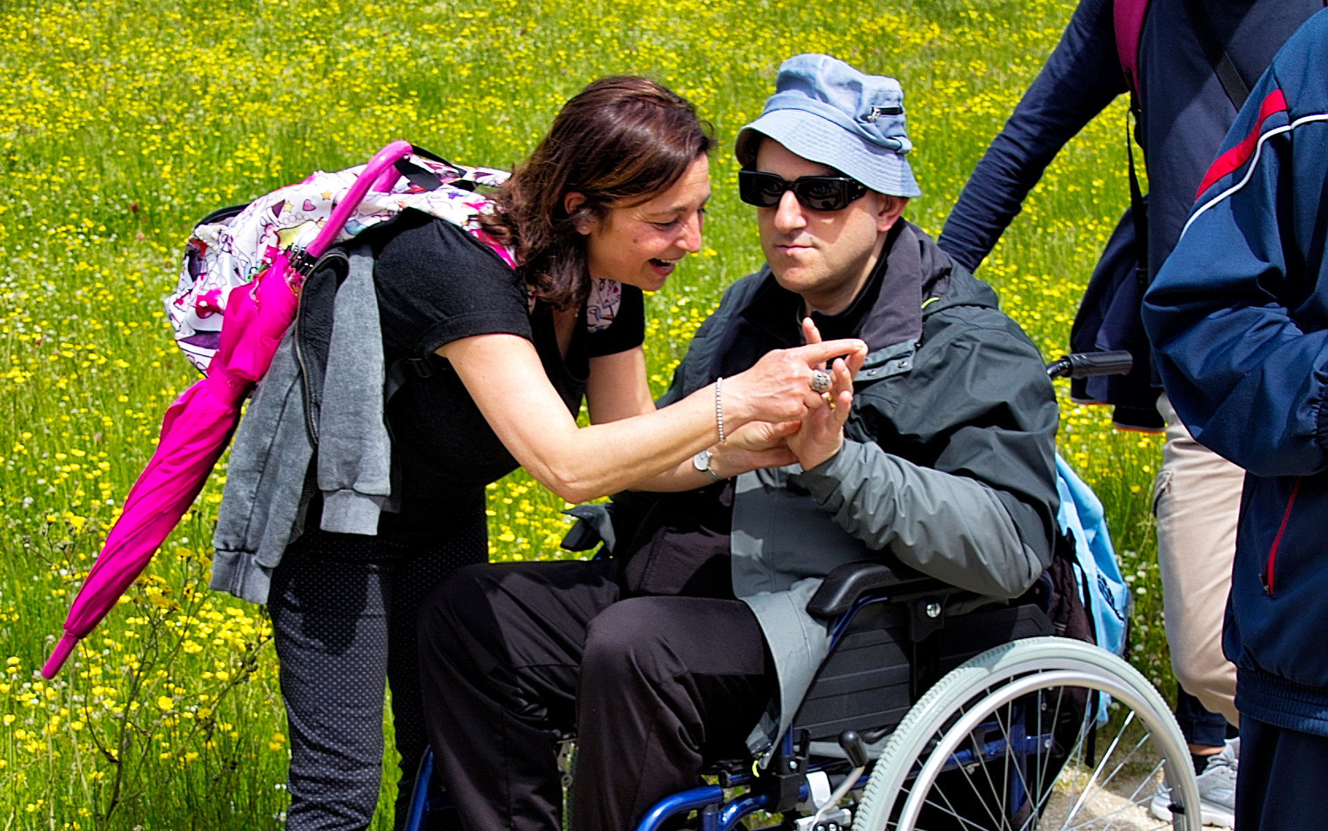 Su un sentiero sterrato un'educatrice comunica in Malossi con un uomo sordocieco con disabilità motoria