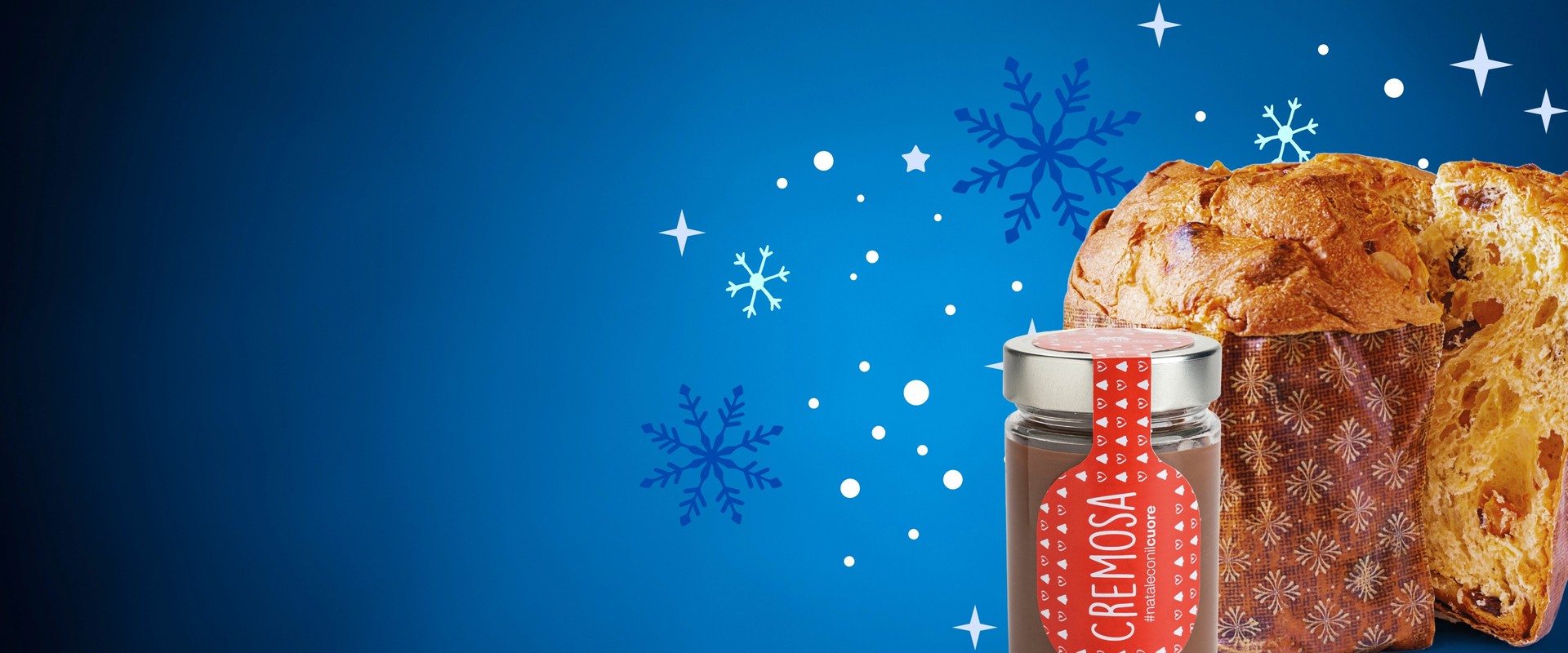 Su uno sfondo blu decorato con un motivo a fiocchi di neve bianchi e blu, spiccano i prodotti del Set goloso: un panettone e un barattolo di crema gianduja