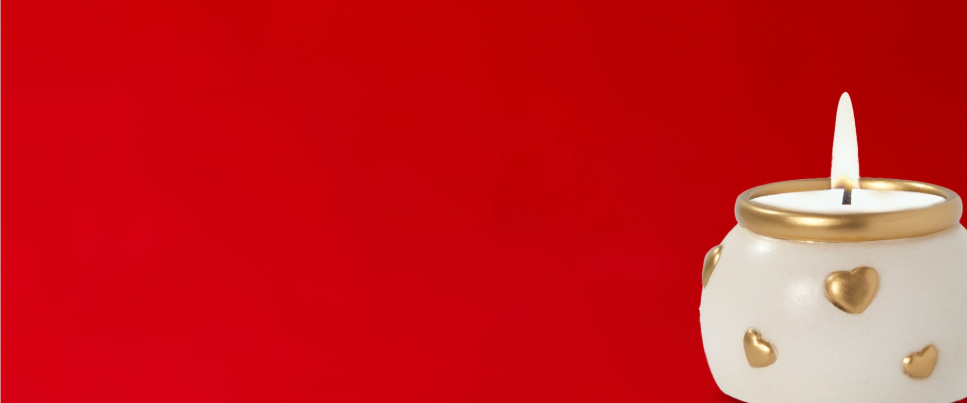Portacandele in ceramica bianca e decorato con cuoricini dorati. Su sfondo rosso intenso