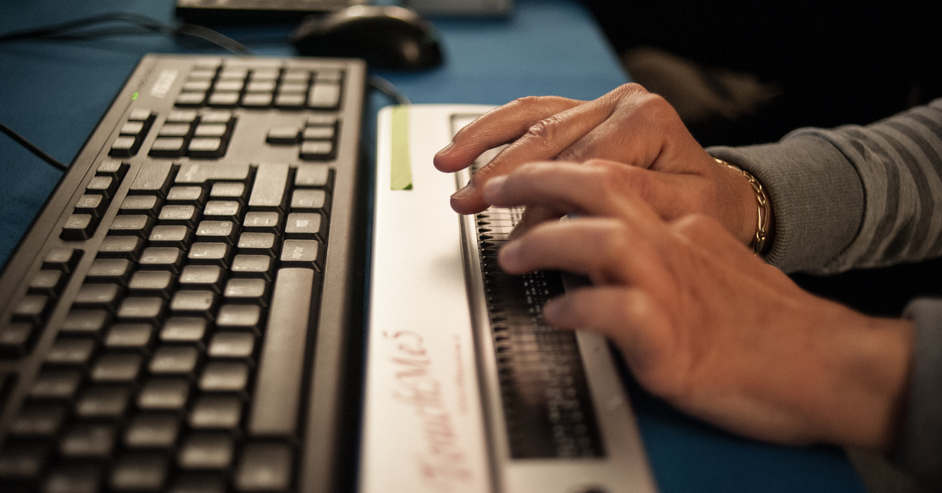 Due mani sono fotografate mentre toccano una barra braille.