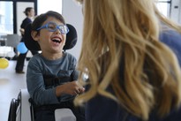 Nicola, bambino utente della Lega del Filo d’Oro, scherza con un’operatrice in un momento di gioco e relazione, simbolo di crescita, fiducia e inclusione per le persone con sordocecità.