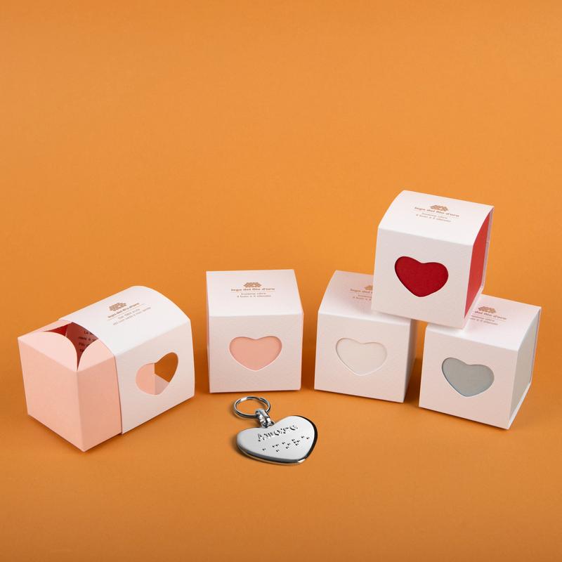 Bomboniere Cuore con Portachiavi cuore su sfondo arancione. I colori delle bomboniere sono rosa, bianco, rosso, celeste