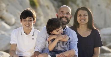 Agostino e la sua famiglia in una bellissima foto di famiglia seduti sugli scogli al mare