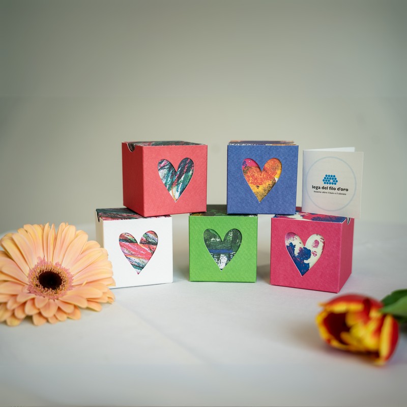 Le 5 versioni delle Bomboniere Pop col loro bigliettino personalizzabile, affiancate da fiori colorati