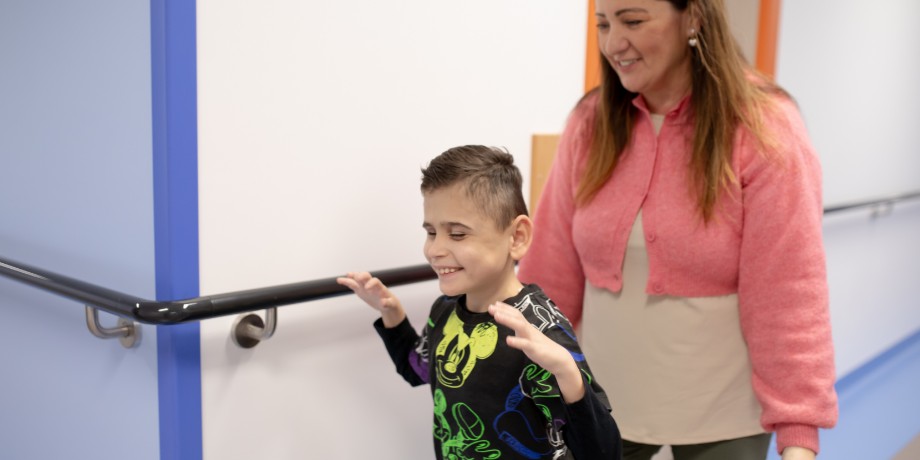 Matteo cammina e ride con l'educatrice nei corridoi del Centro Nazionale di Osimo