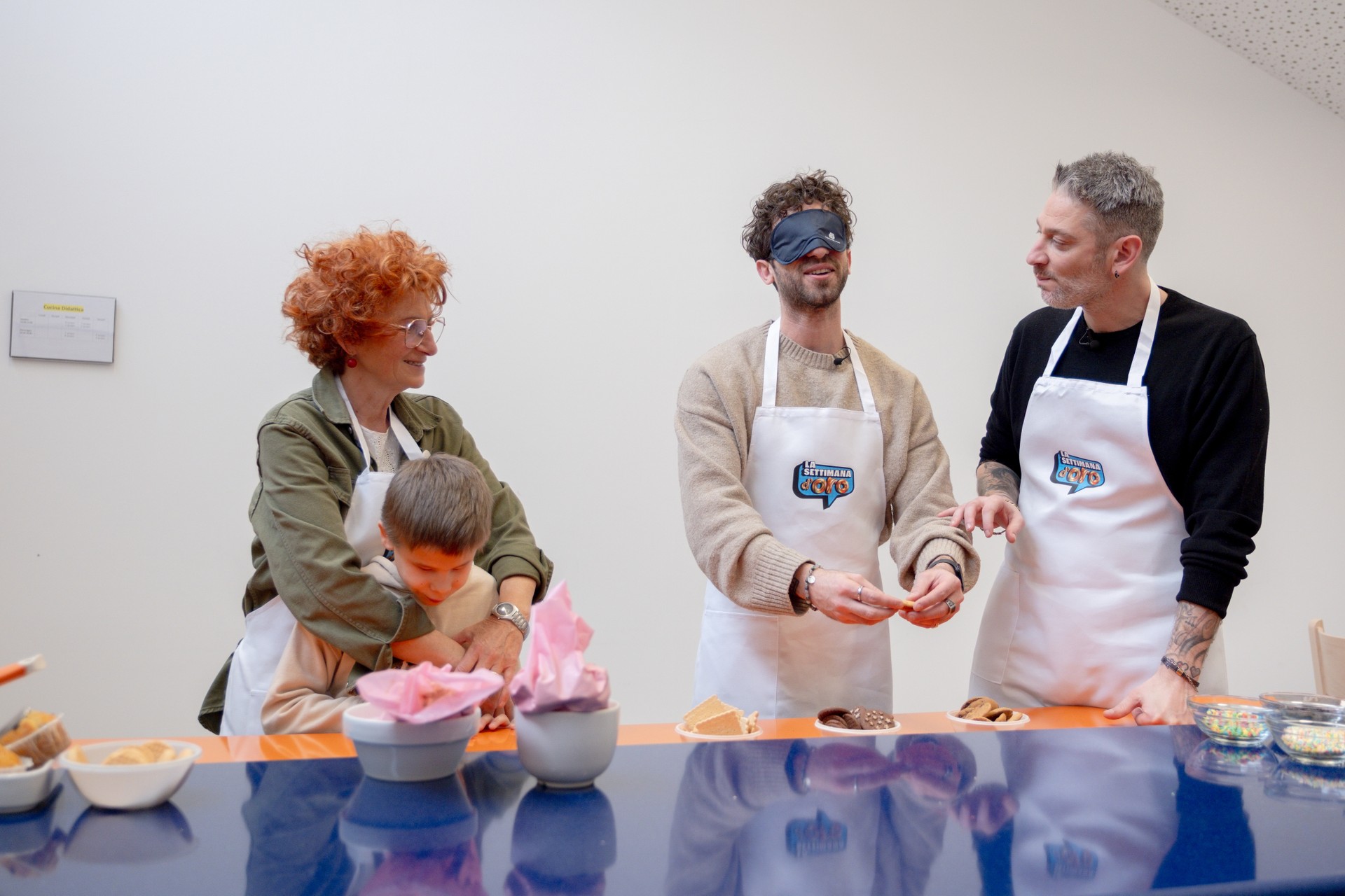 I creators Edoardo Tavassi e Damiano Giordano (che è bendato) sono in cucina insieme al nostro utente Matteo. Insieme alla sua educatrice, provano a preparare dei biscotti