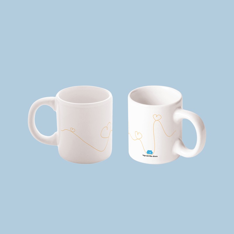 Due tazzine da caffè in ceramica bianca con manico, decorate con il logo della Lega del Filo d'Oro e una grafica di un filo dorato che disegna dei cuori tutto intorno.