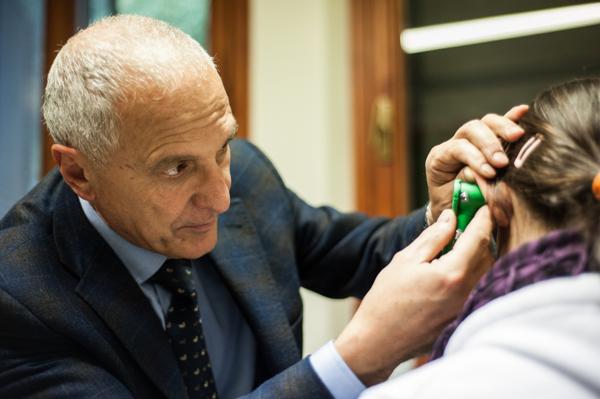 Il dott. Brozzi sta visitando una paziente utilizzando una particolare attrezzatura per la misurazione dell'udito all'interno dell'ambulatorio del Centro Nazionale