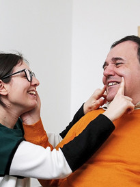 Alberto, utente adulto del Centro di Osimo, posa la mano sul viso di una operatrice, che sorridendo disegna con le dita un sorriso anche sul viso di lui