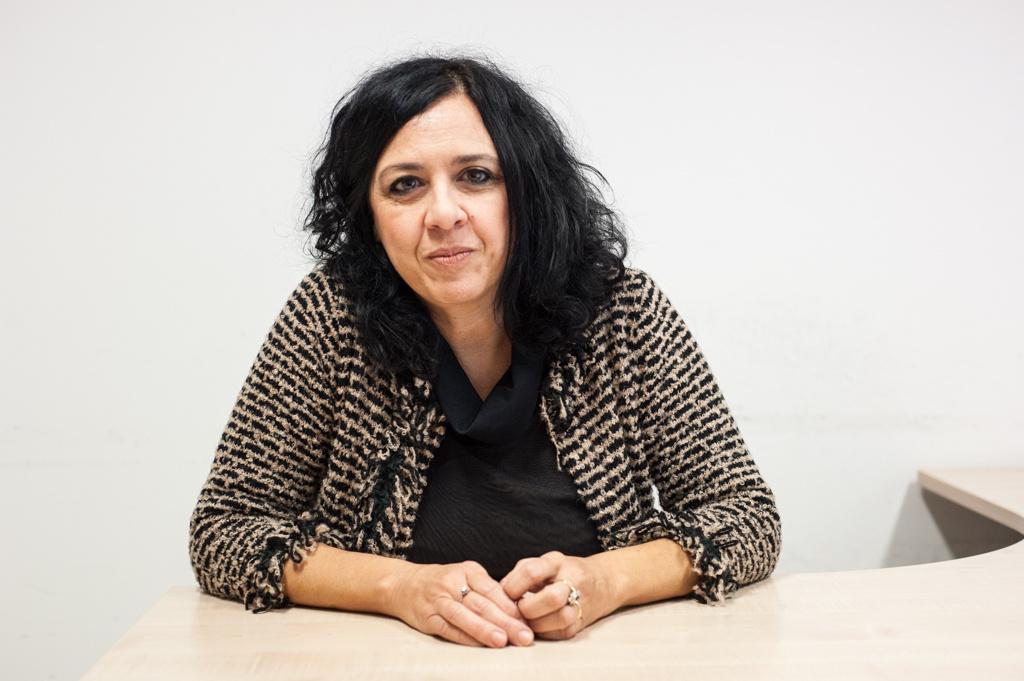 Laura Mondaini seduta alla sua scrivania, sorride guardando la fotocamera.