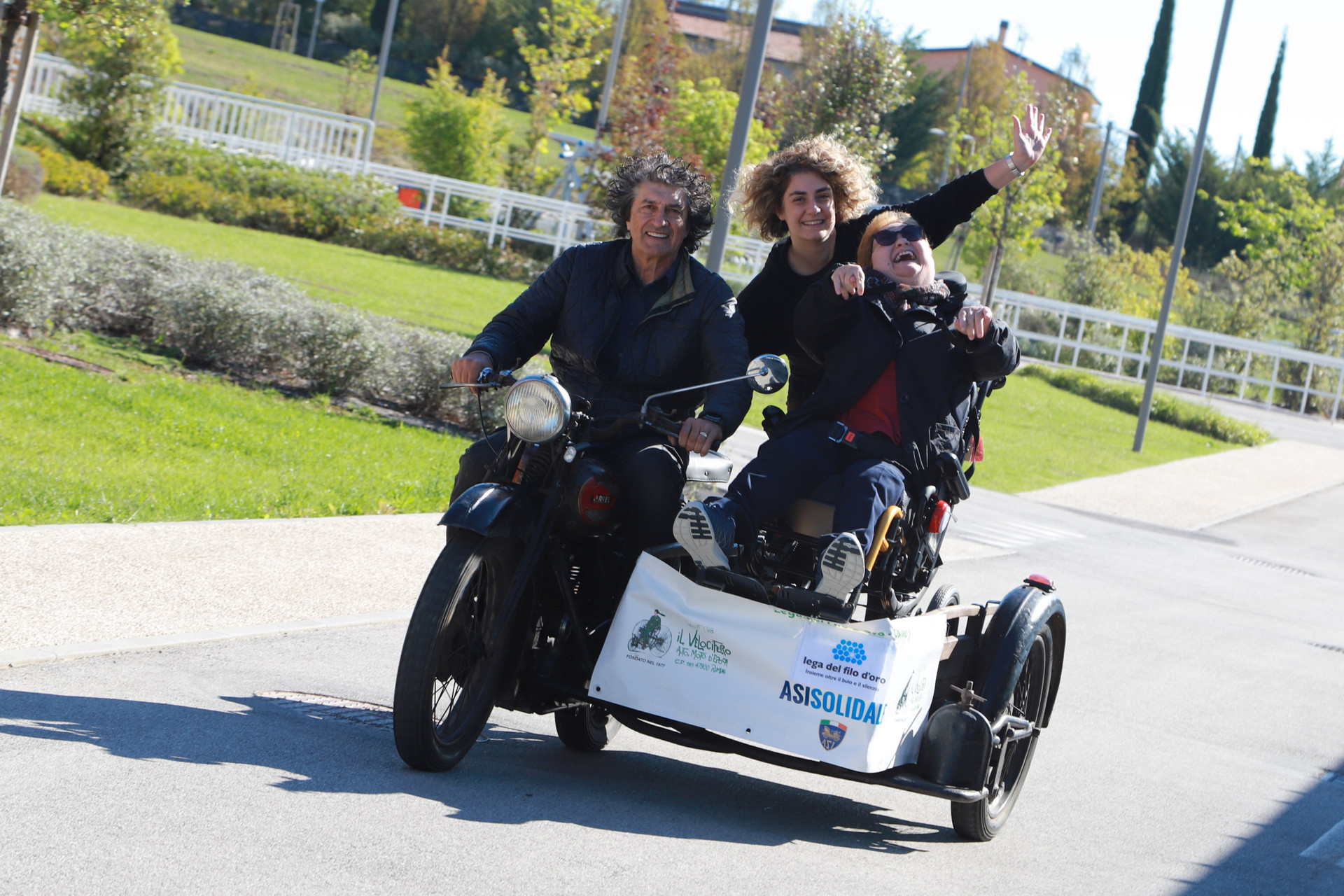 Paola, accompagnata dalla sua educatrice e da un pilota, sorride felice su un sidecar al Centro Nazionale. Un momento di gioia e condivisione in un ambiente sicuro e stimolante.