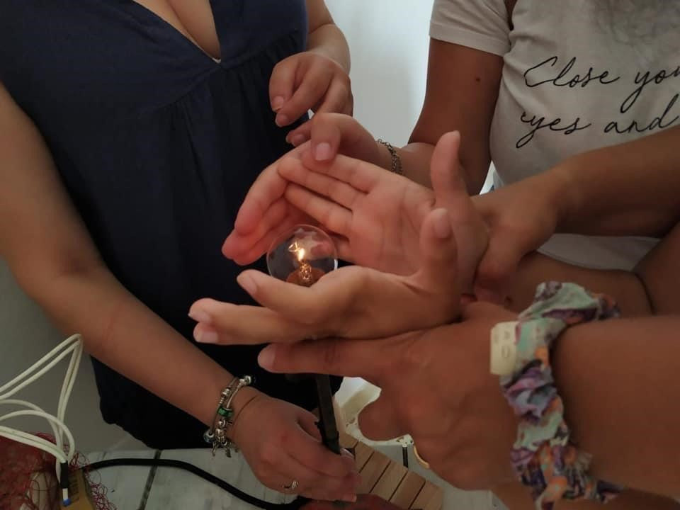 Una lampadina tenuta stretta tra le mani di alcune persone. 