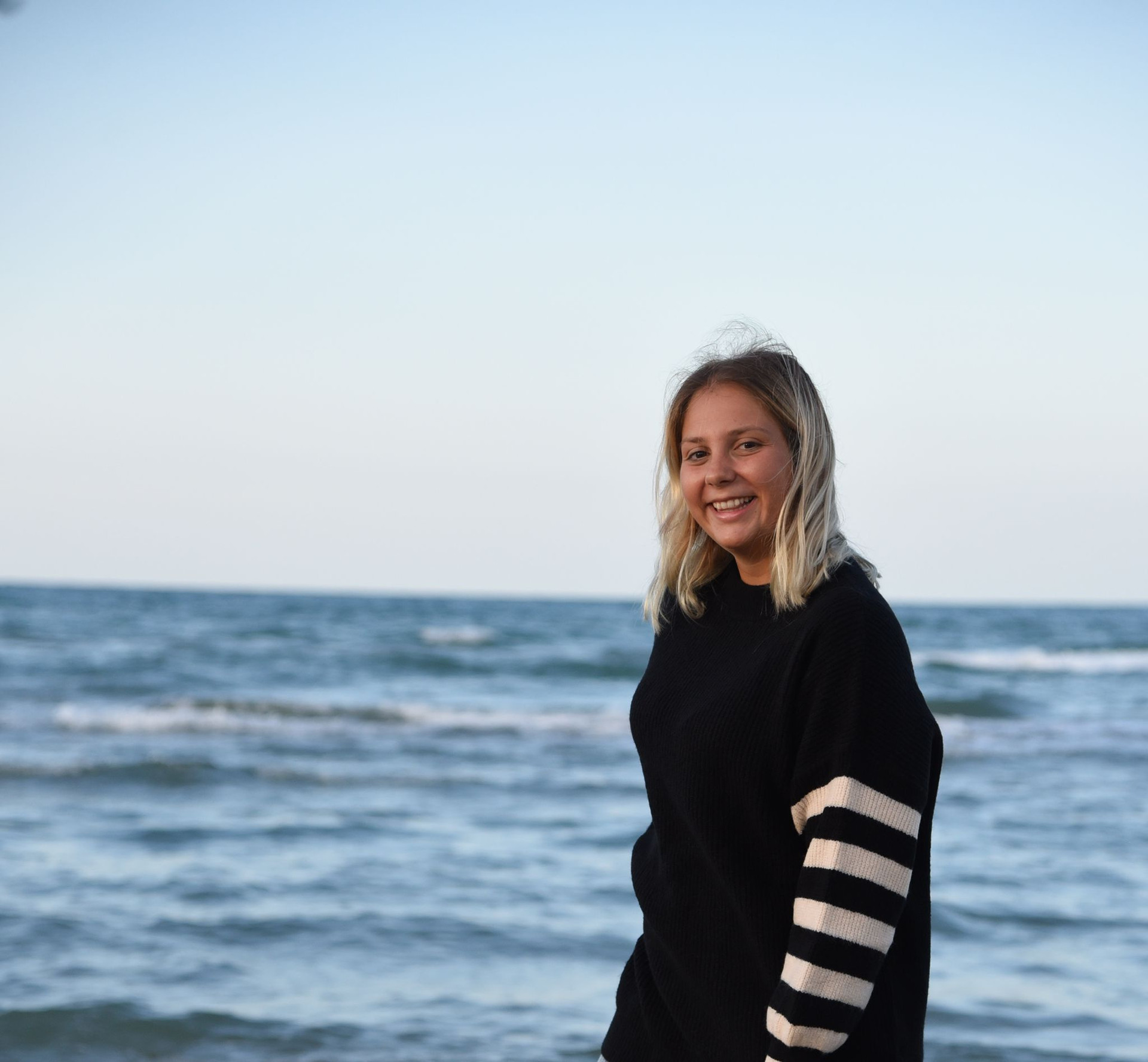 Alice, volontaria della Lega del Filo d'Oro, sorride e alle sue spalle si vede il mare