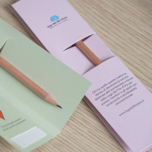 Bomboniera con matita piantabile e cartoncino pregiato disponibile in 5 varianti di colore: dettaglio versioni verde e rosa con visione del retro del cartoncino dove si spiega la scelta delle bomboniere solidali 11