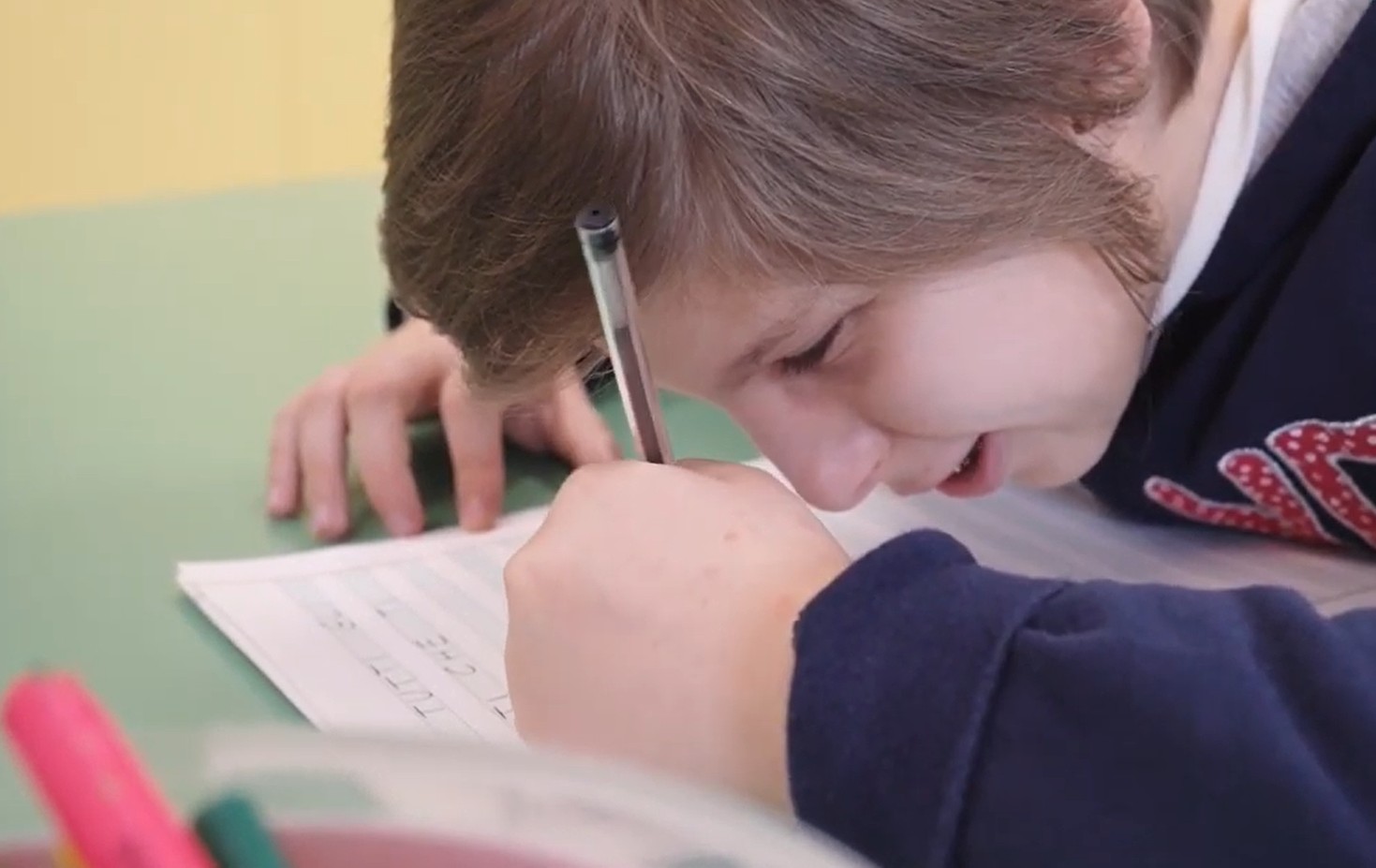 Erica, giovane utente con Sindrome di Charge, scrive su un foglio durante una lezione