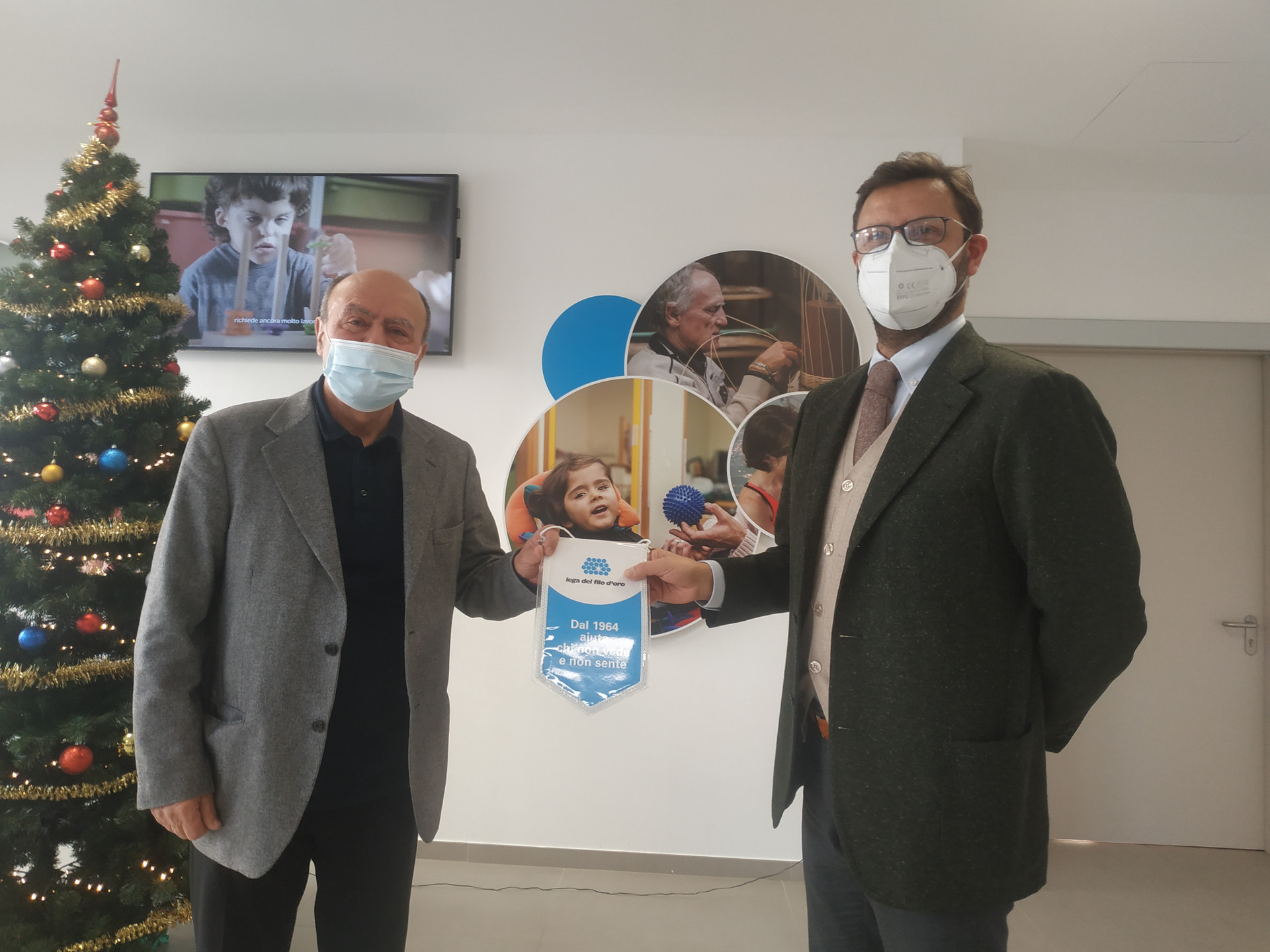 Il Presidente Rossano Bartoli scambia il gagliardetto della Lega del FIlo d'Oro in segna di partnership con un altro uomo.