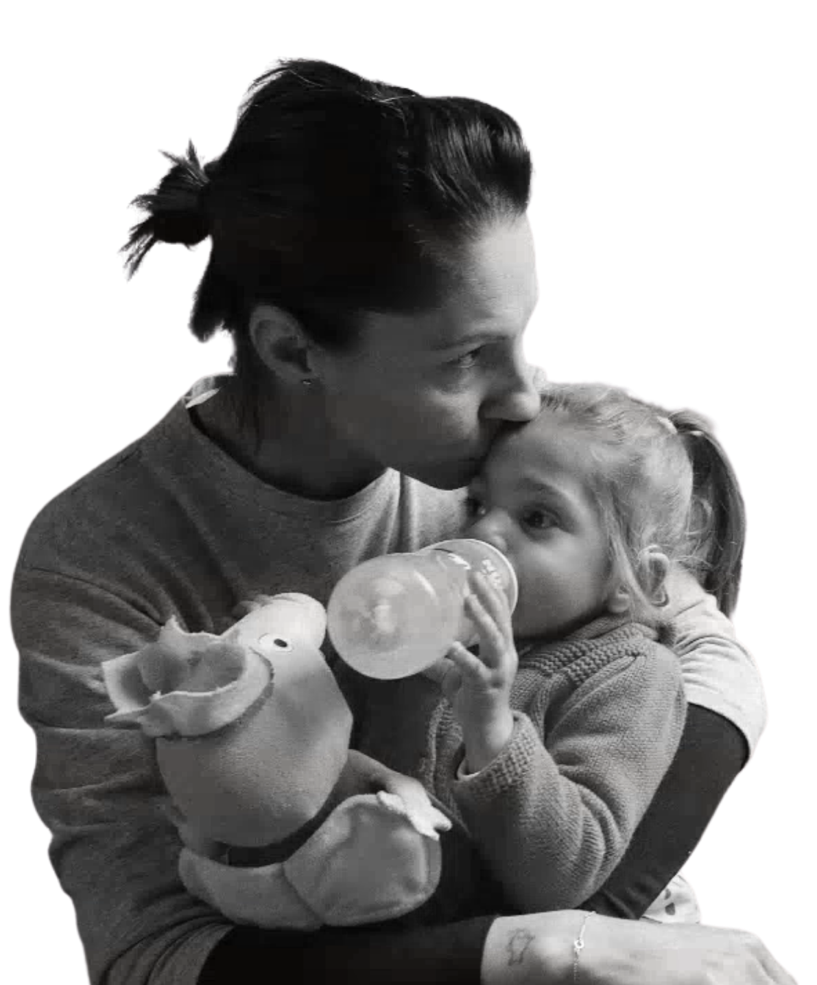 Foto in bianco e nero di Sveva che beve dal biberon in braccio alla mamma, che le dà un bacio sulla fronte