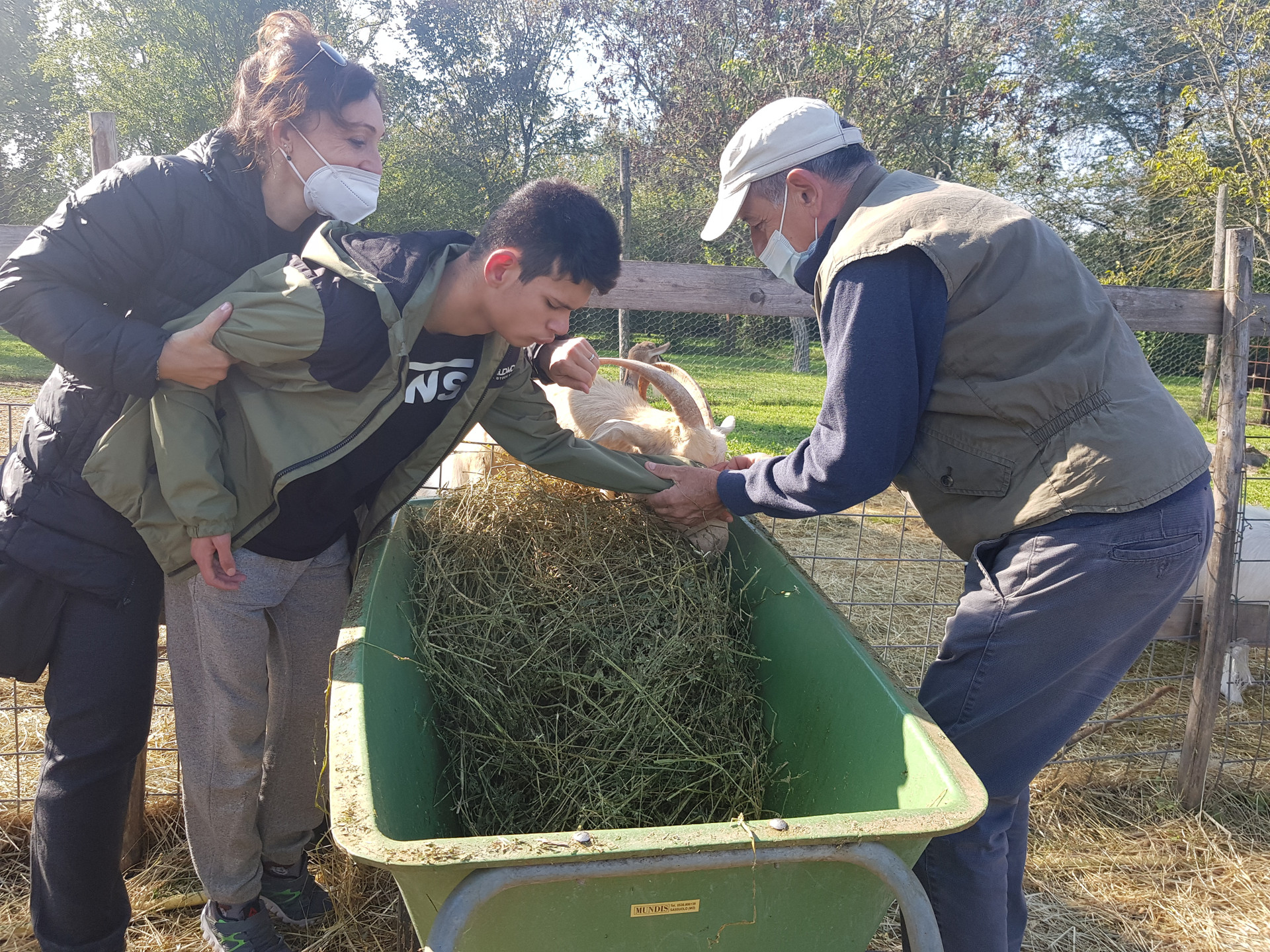 Un giovane utente insieme ad altre due persone accarezza una capretta