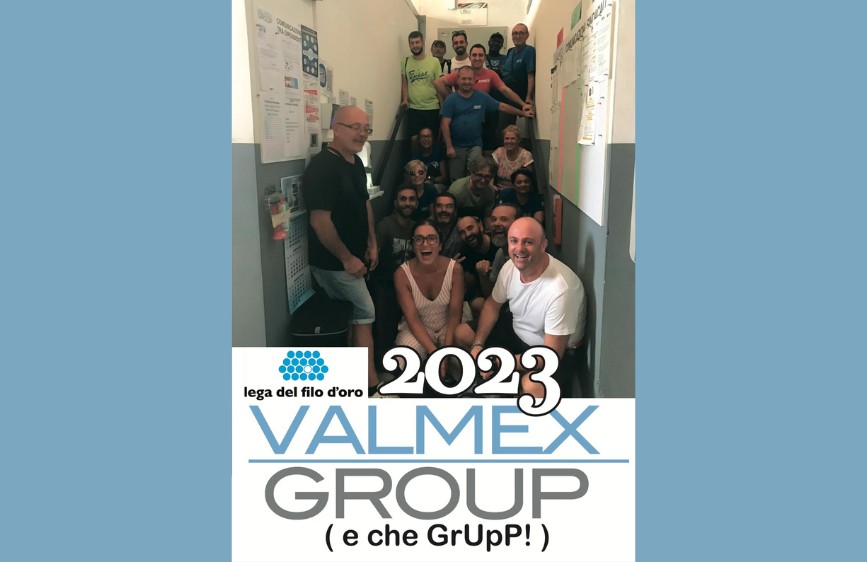 L'immagine è un poster verticale con una foto di gruppo di circa 15 persone, sorridenti e disposte su una scala interna, con l'anno "2023" e i loghi "lega del filo d'oro" e "VALMEX GROUP (e che GruPP!)" in basso. Il gruppo sembra informale e festoso.