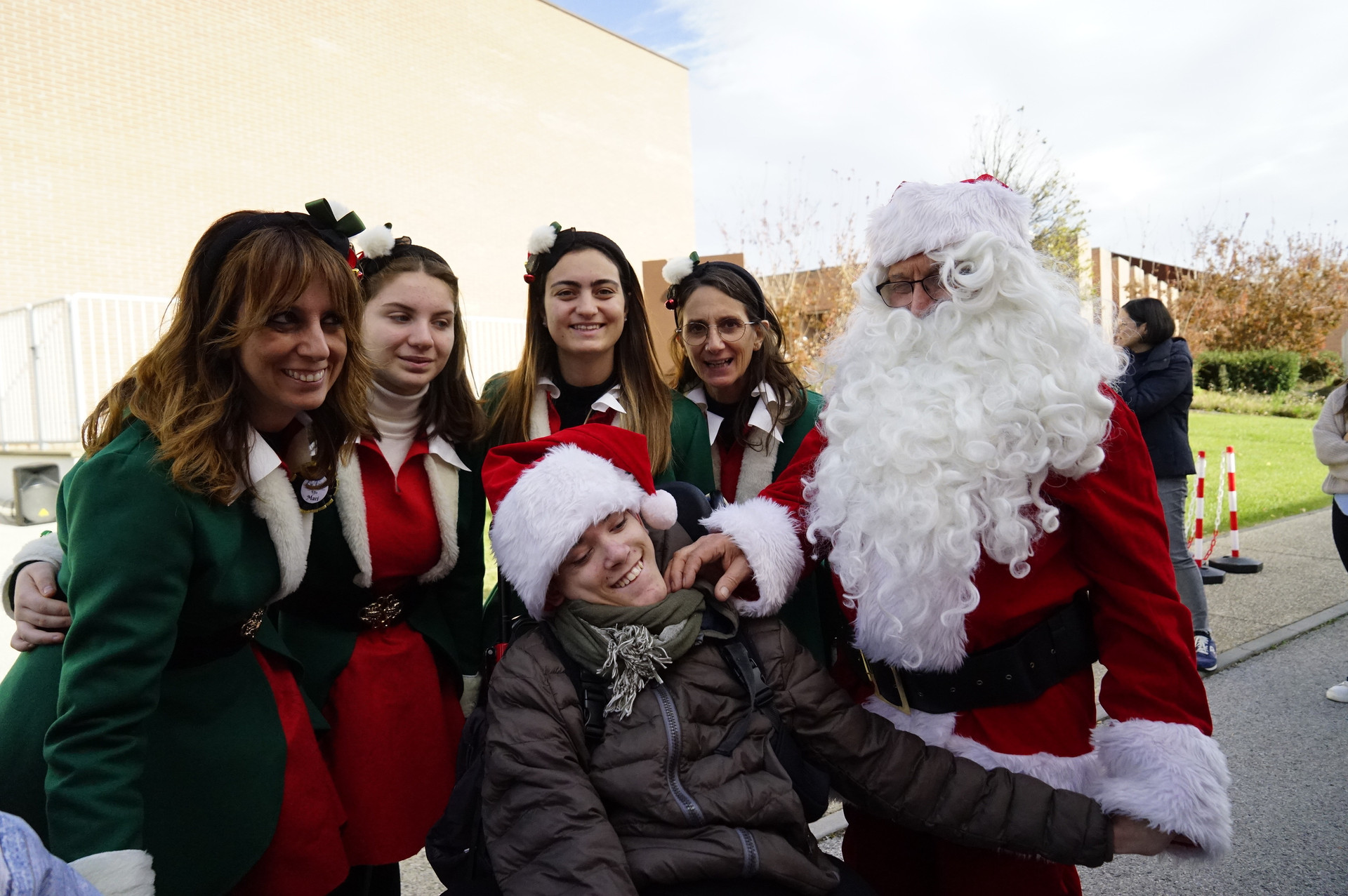Utente e operatrici vestiti da Babbo Natale ed elfi sorridenti.