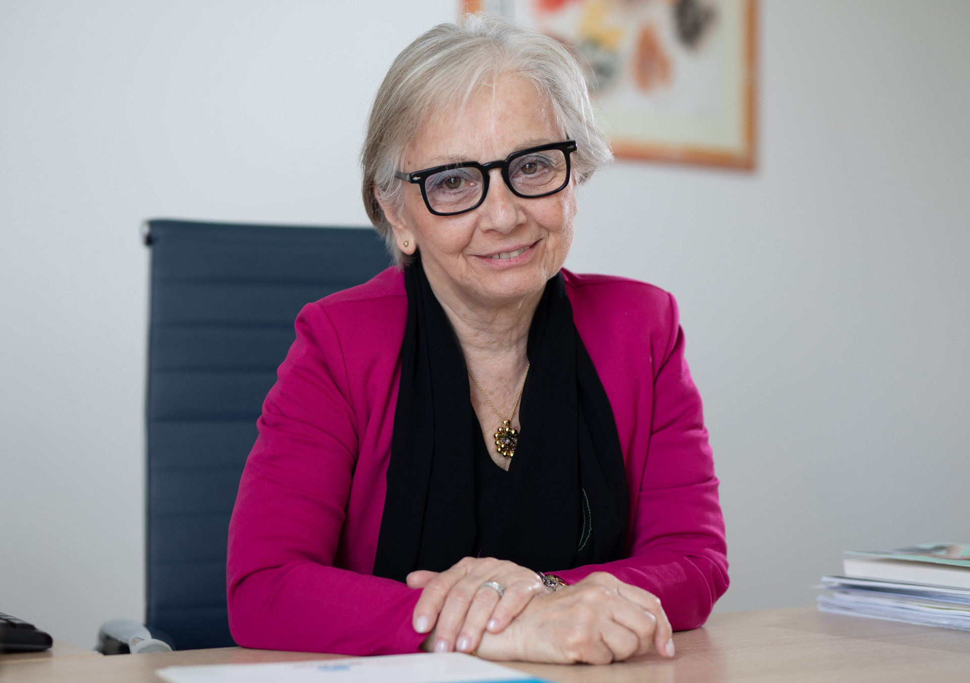 Patrizia Ceccarani, Segretario del Comitato Tecnico Scientifico ed Etico della Lega del Filo d'Oro, seduta nel suo ufficio sorride di fronte alla fotocamera. Indossa un vestito nero con una giacca fucsia.