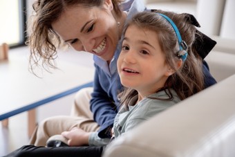 Letizia è seduta e viene presa affettuosamente per il braccio dalla mamma che la guarda