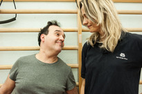 Alberto utente adulto a fianco della fisioterapista Francesca mentre esegue un esercizio alla spalliera in una delle palestre della Lega del Filo d'Oro.