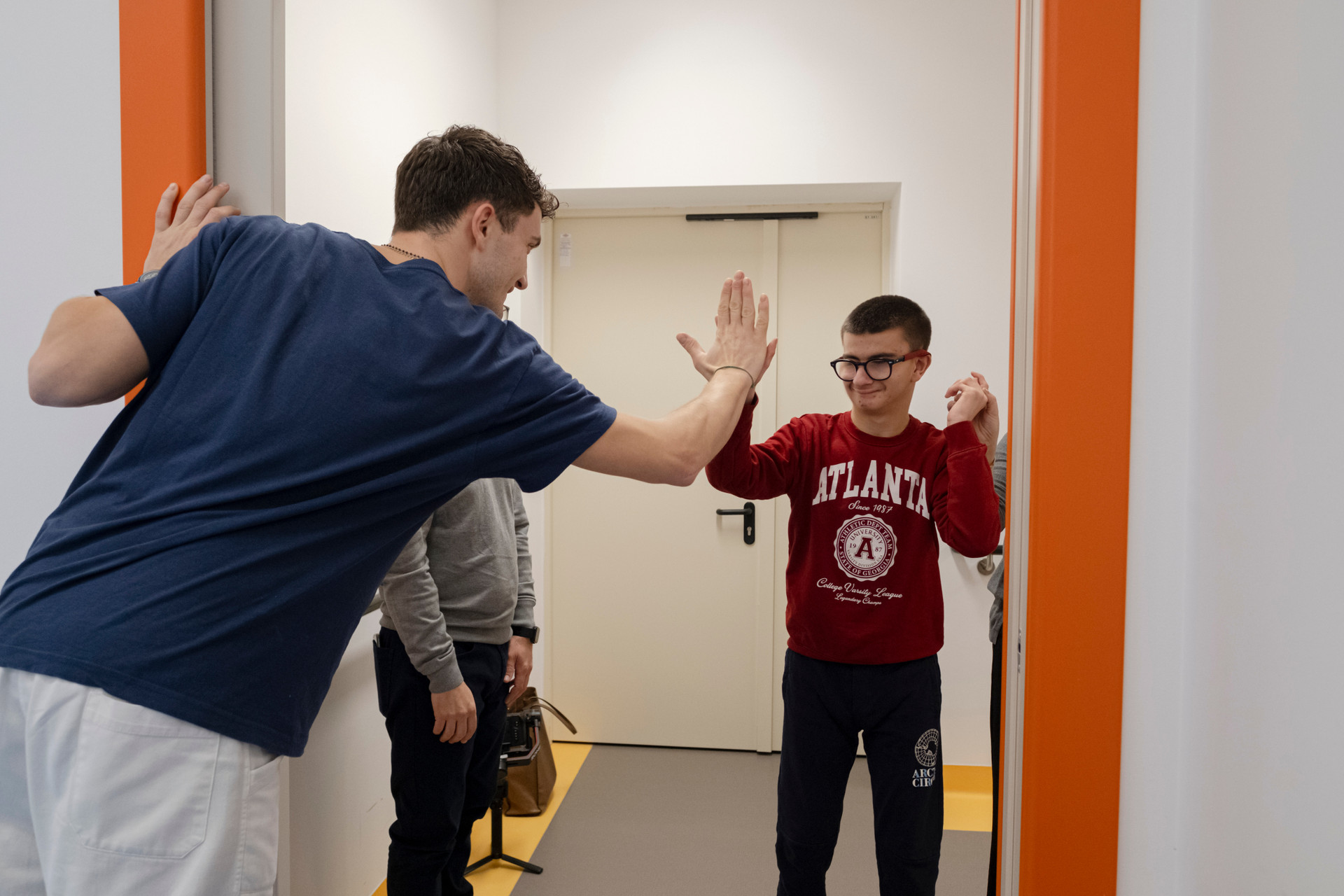 Un ragazzo batte il cinque a un educatore, fiero del traguardo raggiunto insieme: un momento di gioia e complicità che racconta il valore dell’impegno condiviso.