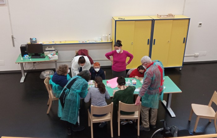 Alcuni operatori e utenti della sede di Novara sono attorno ad un tavolo e svolgono un laboratorio creativo. 