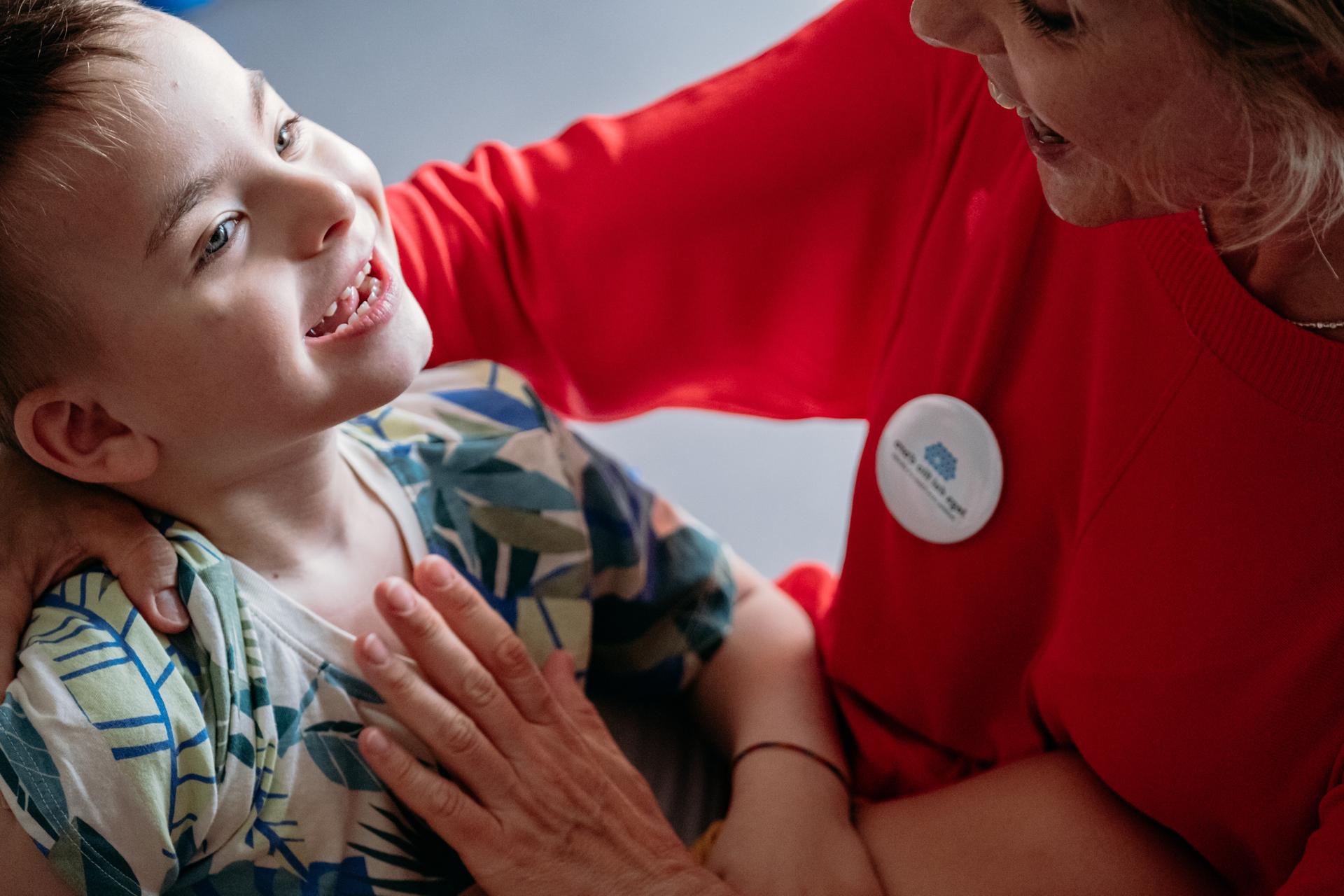 Edoardo in braccio alla sua educatrice giocano e sorridono