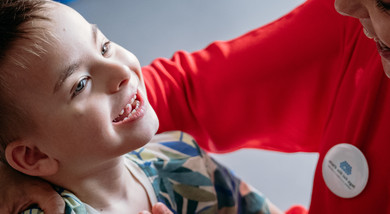 Edoardo in braccio alla sua educatrice giocano e sorridono