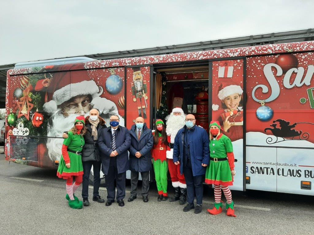 Il bus di Santa Claus in visita al Centro Nazionale della Lega del Filo d'Oro. Alcuni dipendenti della Lega del Filo d'Oro posano con Babbo Natale e 3 elfe.