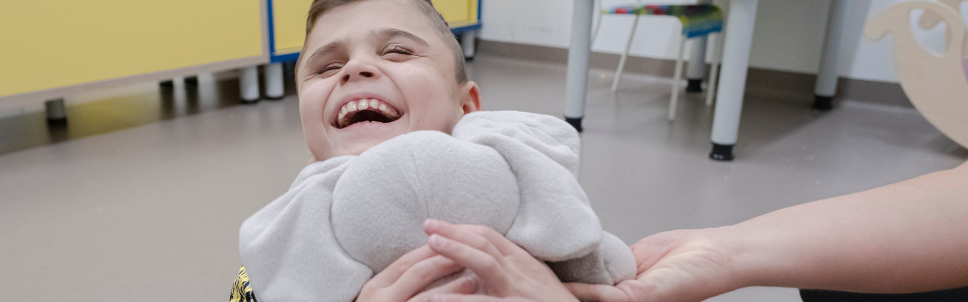 Matteo, un utente della Lega del Filo d'Oro gioca con il suo peluche di Elefante e ride