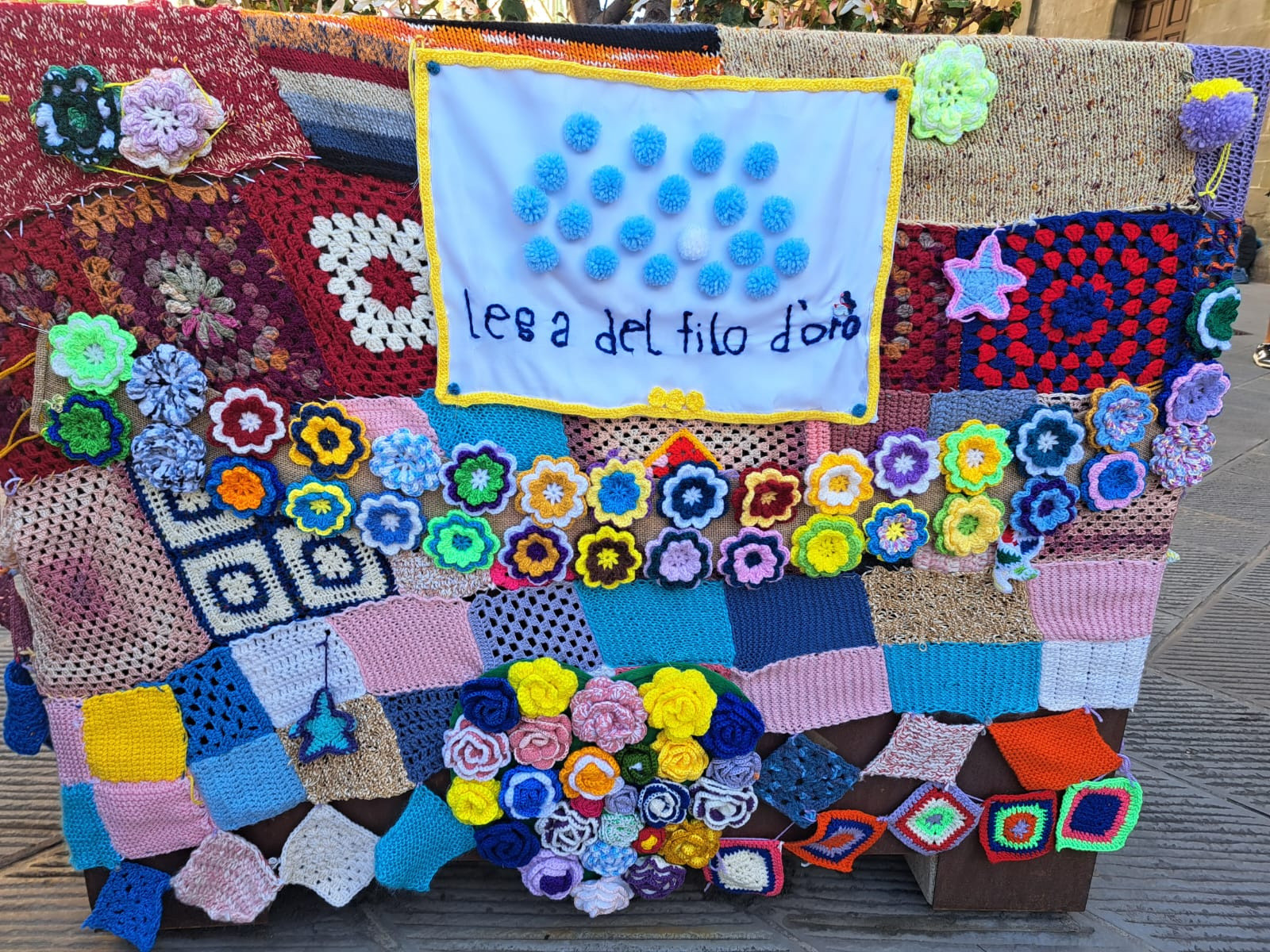 La Lega del Filo d’Oro ha aderito e promosso lo Yarn Bombing: angolo allestito con le creazioni in maglia. Tra le opere spicca una composizione su fondo bianco con la scritta ricamata in blu “Lega del Filo d’Oro”. Il logo dell’associazione è stato ricreato con pompon azzurri e uno bianco