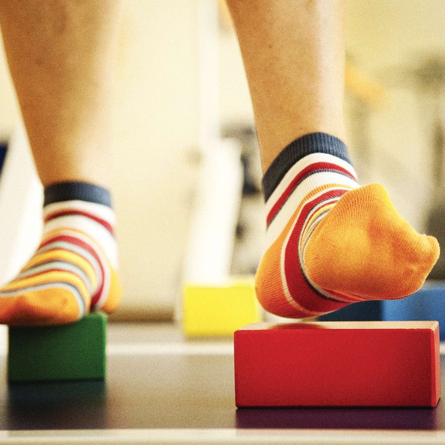 I piedi di un utente durante un attività che prevede di camminare appoggiando i piedi solo su dei cubetti colorati.