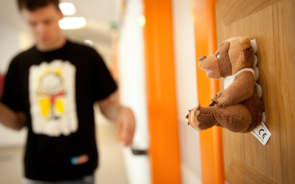 Un segnalino oggettuale con un orsetto di peluche, segnala l'ingresso di un'aula per attività educativo-riabilitative.