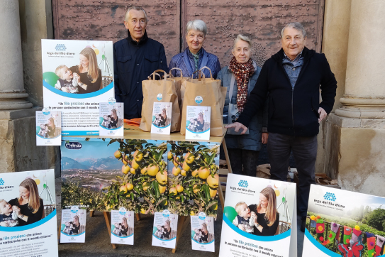 Un gruppo di volontari della Lega del Filo d’Oro posa sorridente davanti a uno stand informativo