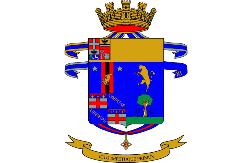 L'immagine mostra un elaborato stemma comunale italiano su sfondo bianco, sormontato da una corona dorata e nastri blu. Lo scudo è diviso in più sezioni con vari simboli, tra cui figure araldiche, una torre, stelle, un toro, un albero e la parola "LIBERTAS", con un motto latino "ICTU IMPETUQUE PRIMUS" su un nastro dorato alla base.