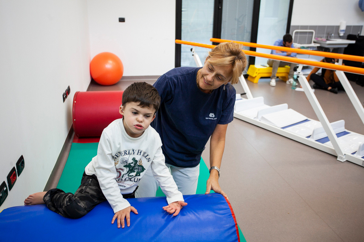Agostino, bambino seguito al Centro di Osimo, fa un esercizio in palestra con la fisioterapista