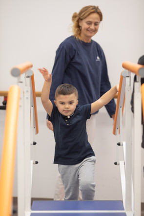 Leonardo, un bambino affetto della sindrome di Charge, sta svolgendo attivitò di fisioterapia con Francesca, fisioterapista del Centro di Osimo della Lega del Filo d'Oro. Leonardo sta salendo delle scale 