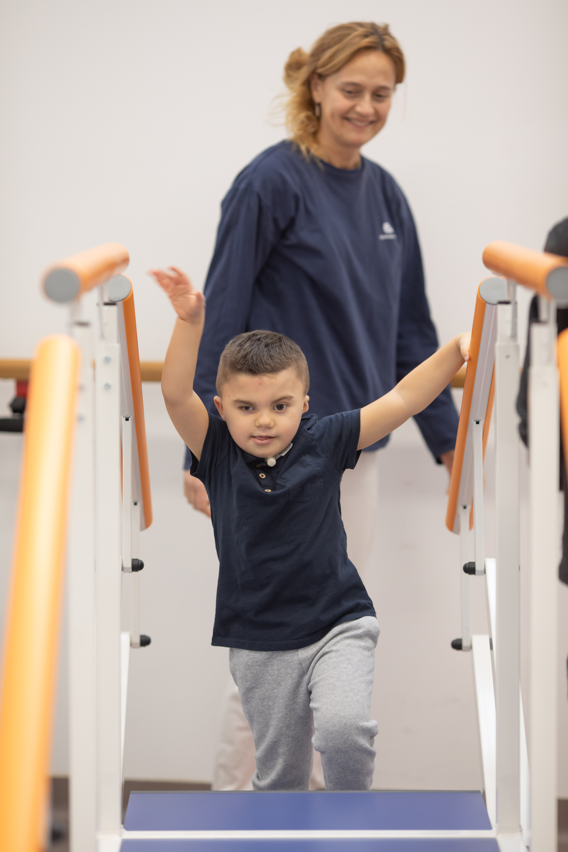 Leonardo, un bambino affetto della sindrome di Charge, sta svolgendo attivitò di fisioterapia con Francesca, fisioterapista del Centro di Osimo della Lega del Filo d'Oro. Leonardo sta salendo delle scale 